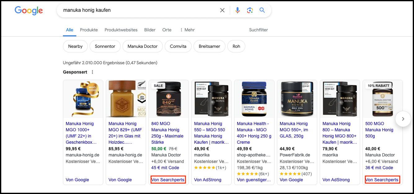 Eine Google-Suche nach "Manuka Honig kaufen" zeigt mehrere gesponserte Produktanzeigen, darunter auch solche von 'Searchperts', einem Google CSS-Partner, hervorgehoben durch die Schaltfläche "Von Searchperts" unter den entsprechenden Produkten.