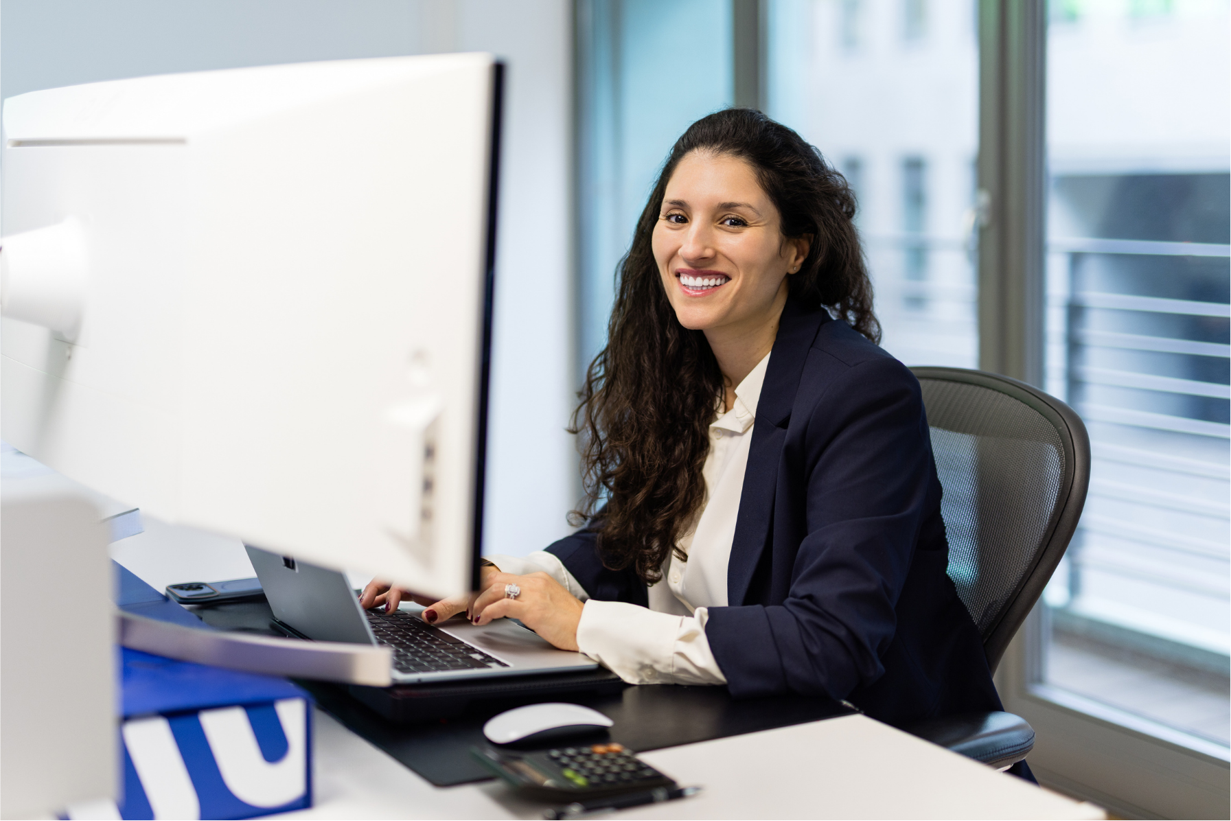 Leila Aarab, Head of Client Success bei Searchperts, bei der Arbeit mit lächelndem Blick in die Kamera